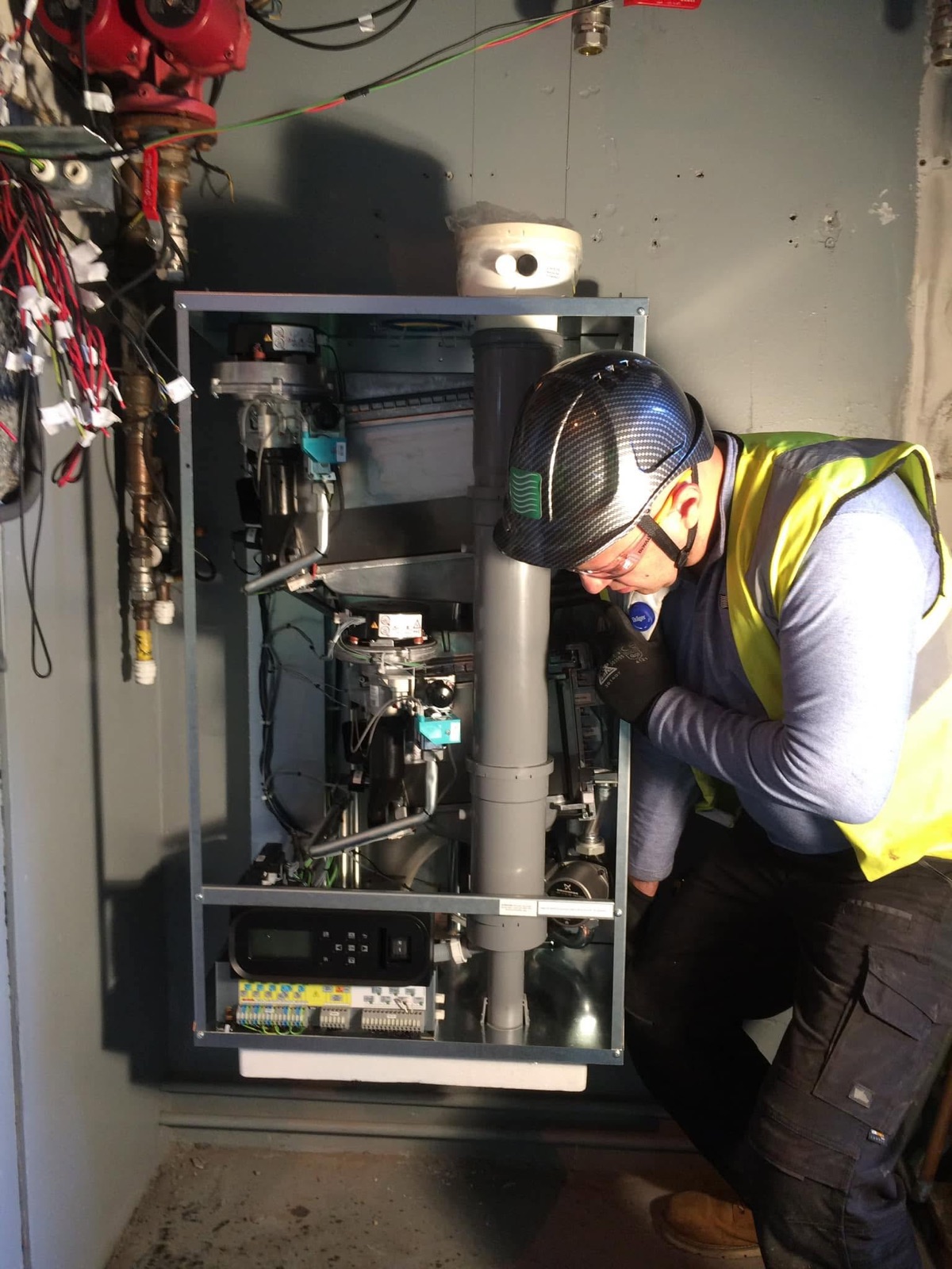 Engineer working on a commercial wall-hung boiler installation, casing off